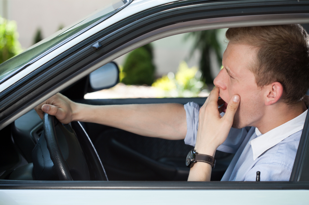 Man driving car while yawning