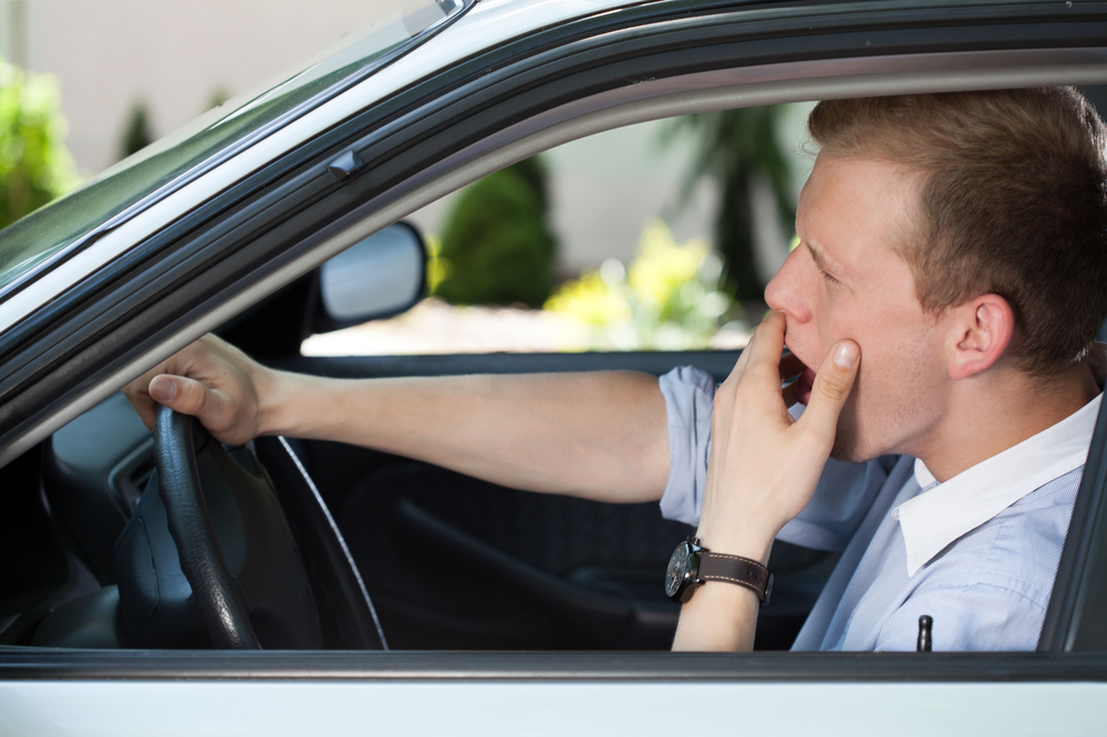 Man driving car while yawning Man driving car while yawning