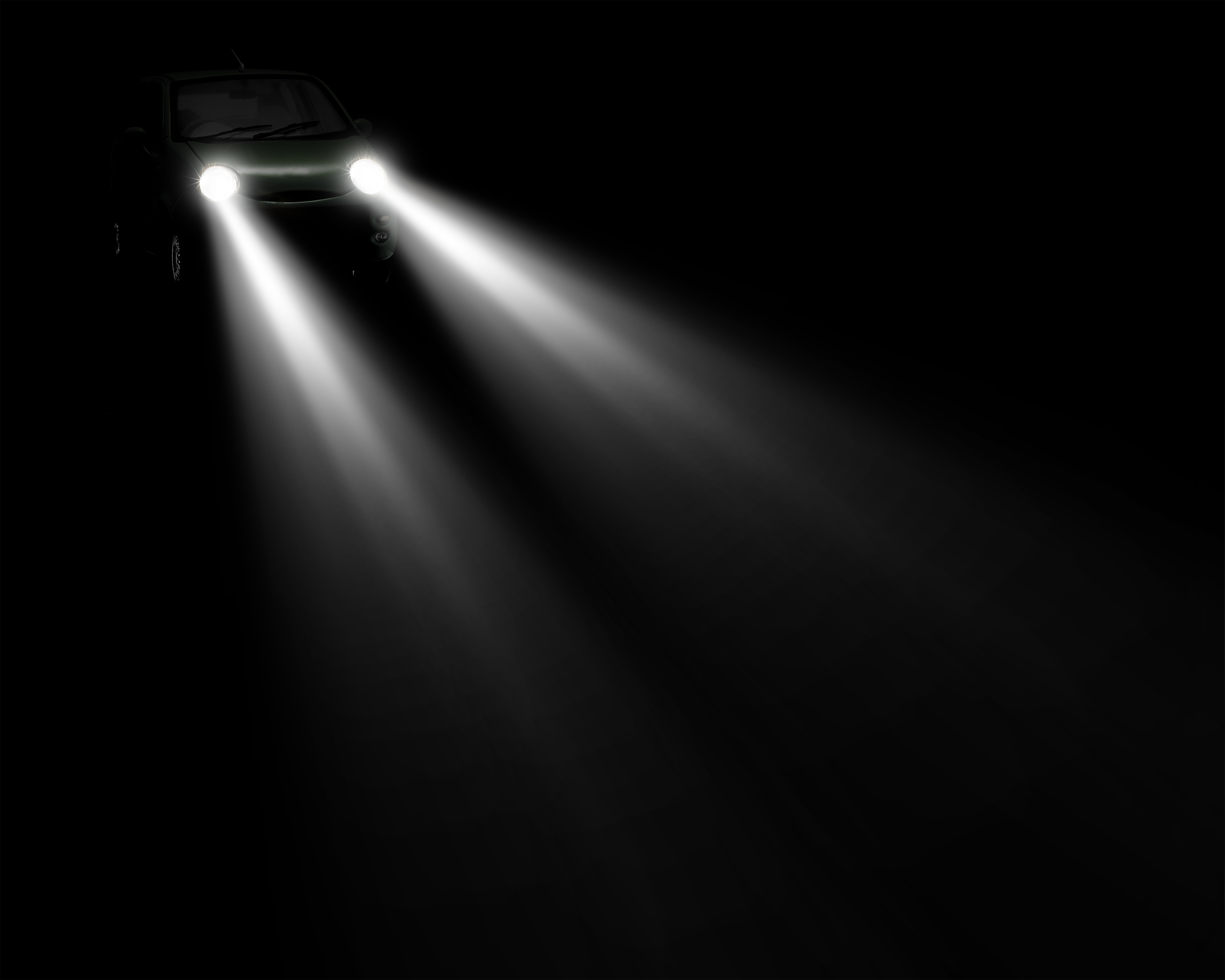 Vehicle in top left corner shining bright headlights on black background