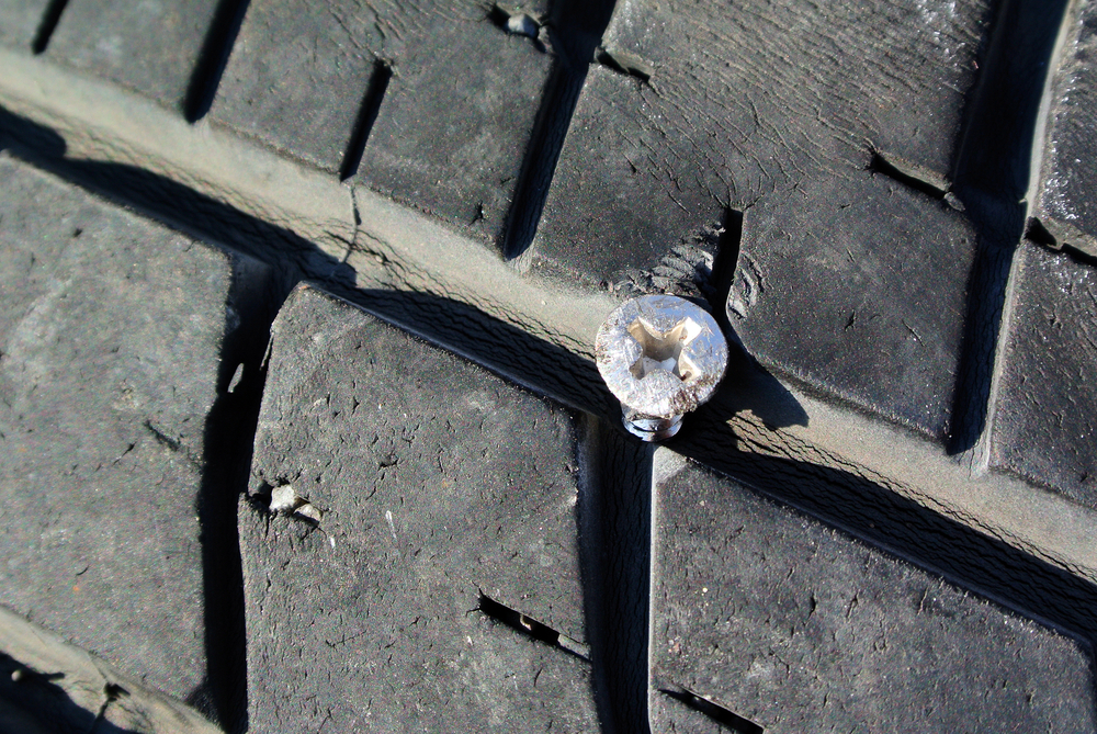 Worn tire tread with nail in it