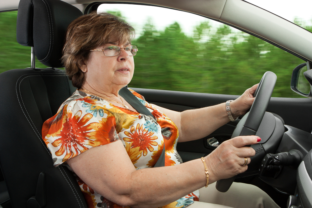 Woman driving in car going past trees