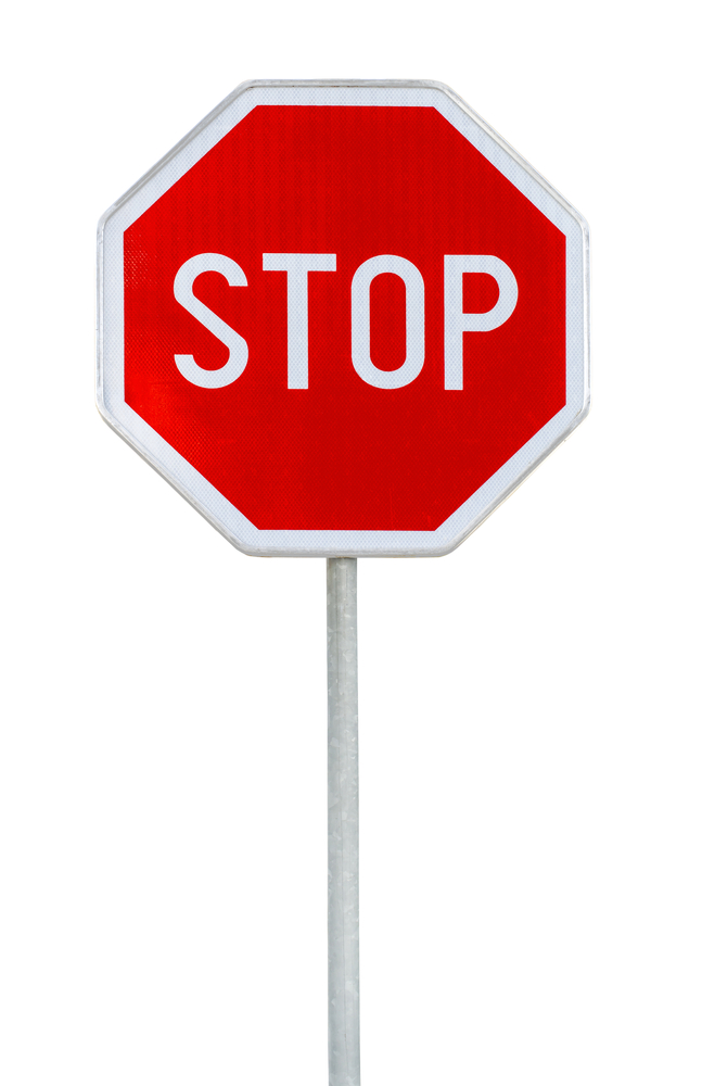 Red octagon metal stop sign attached to silver pole on white background